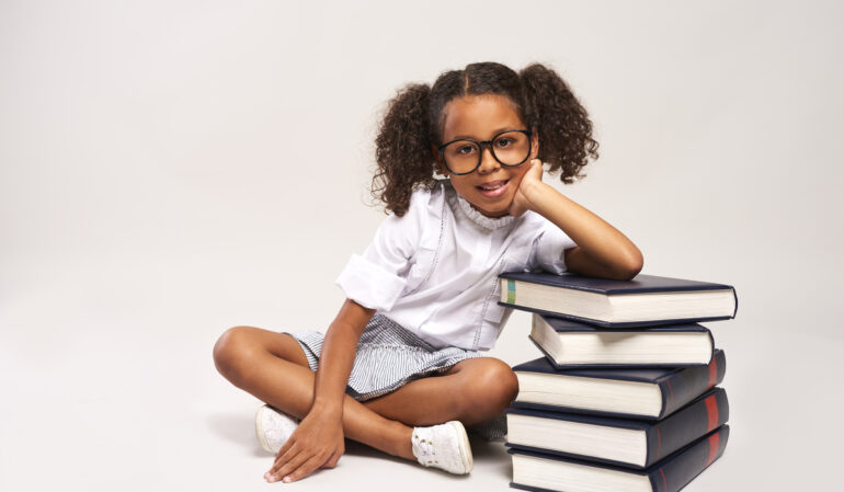 African girl sitting next to stack of books